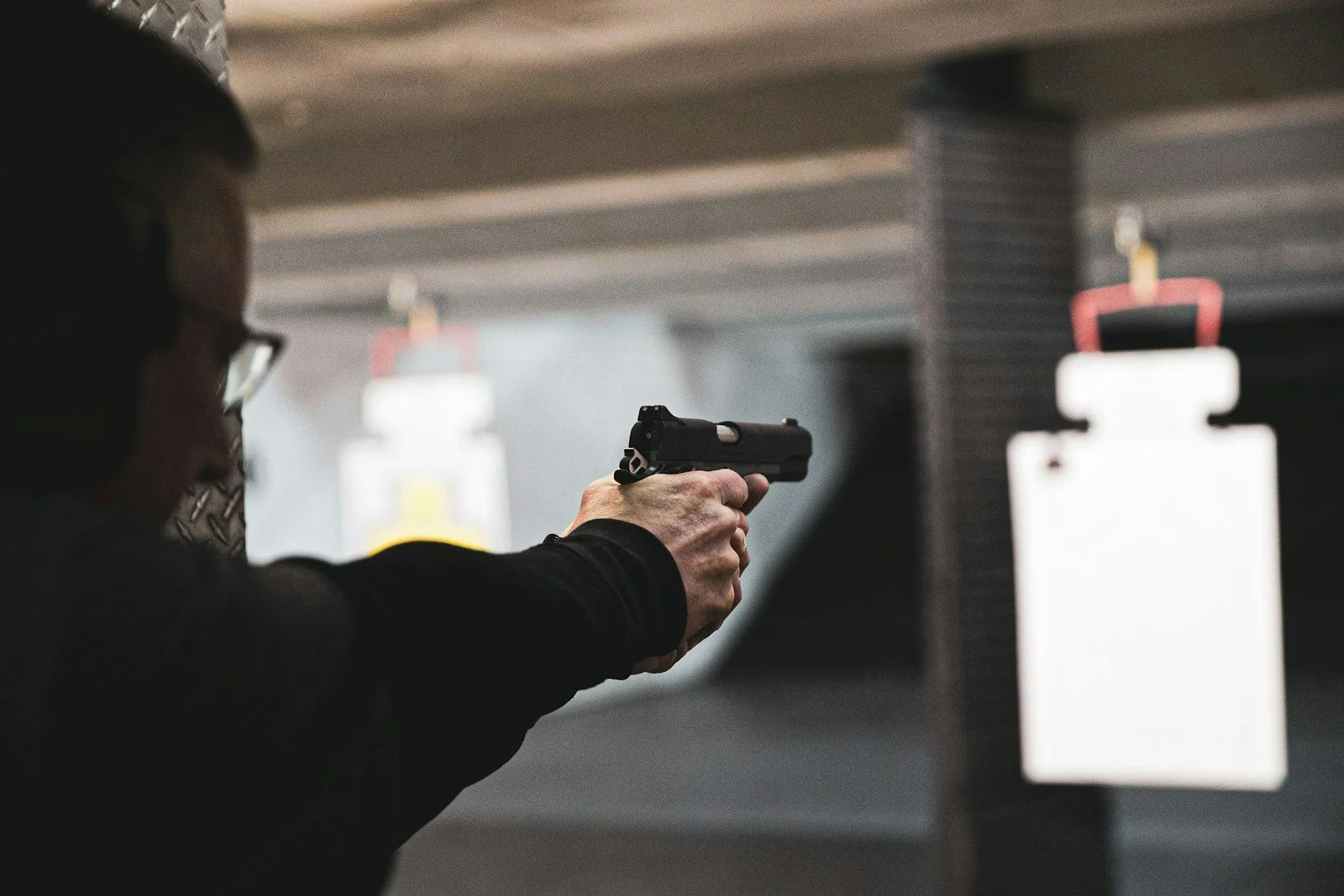 Shooter in an indoor range lane aiming at a target